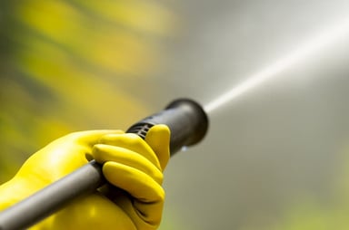 Person using a pressure washer with yellow gloves