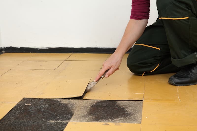 Person repairing floor with flooring material