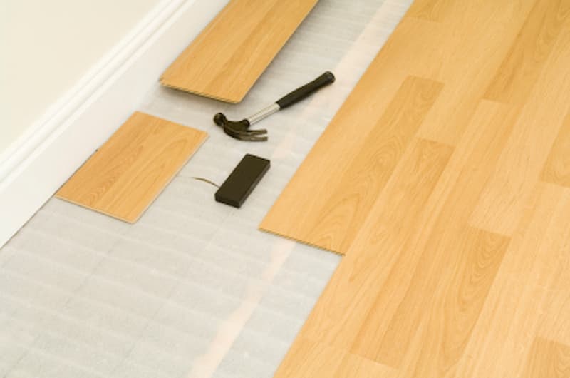 Vinyl flooring installation with tools on wooden floor