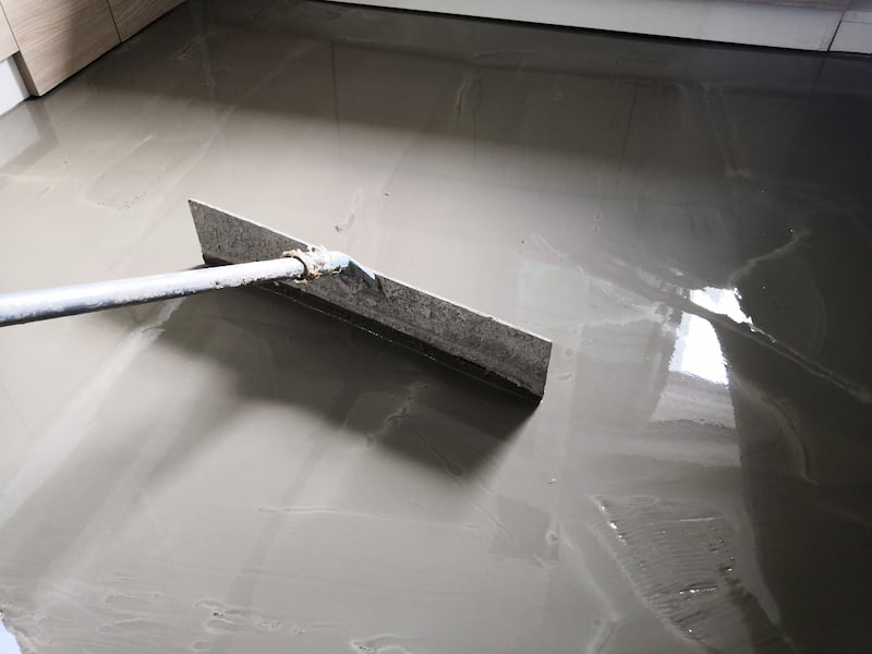 Worker smoothing freshly poured gray concrete floor