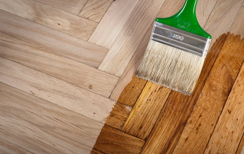 Wood floor being stained with a paintbrush